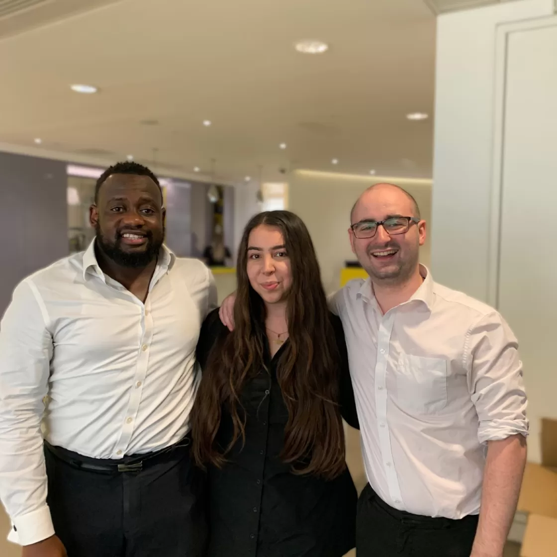 A group of diverse professionals smiling and talking in an office: Empiric recruiters posing for a photo.